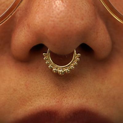 Close up view of a model's nose wearing a 14k yellow gold Beaded Septum