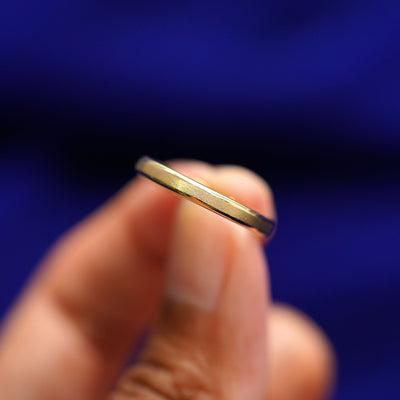 A model holding a Beveled Edge Band tilted to show the side of the ring