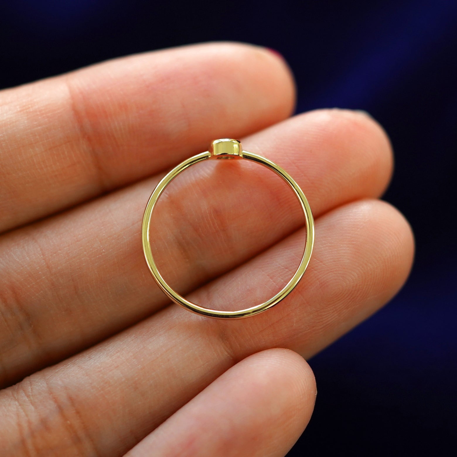 A yellow gold Alexandrite Ring in a model's hand showing the thickness of the band