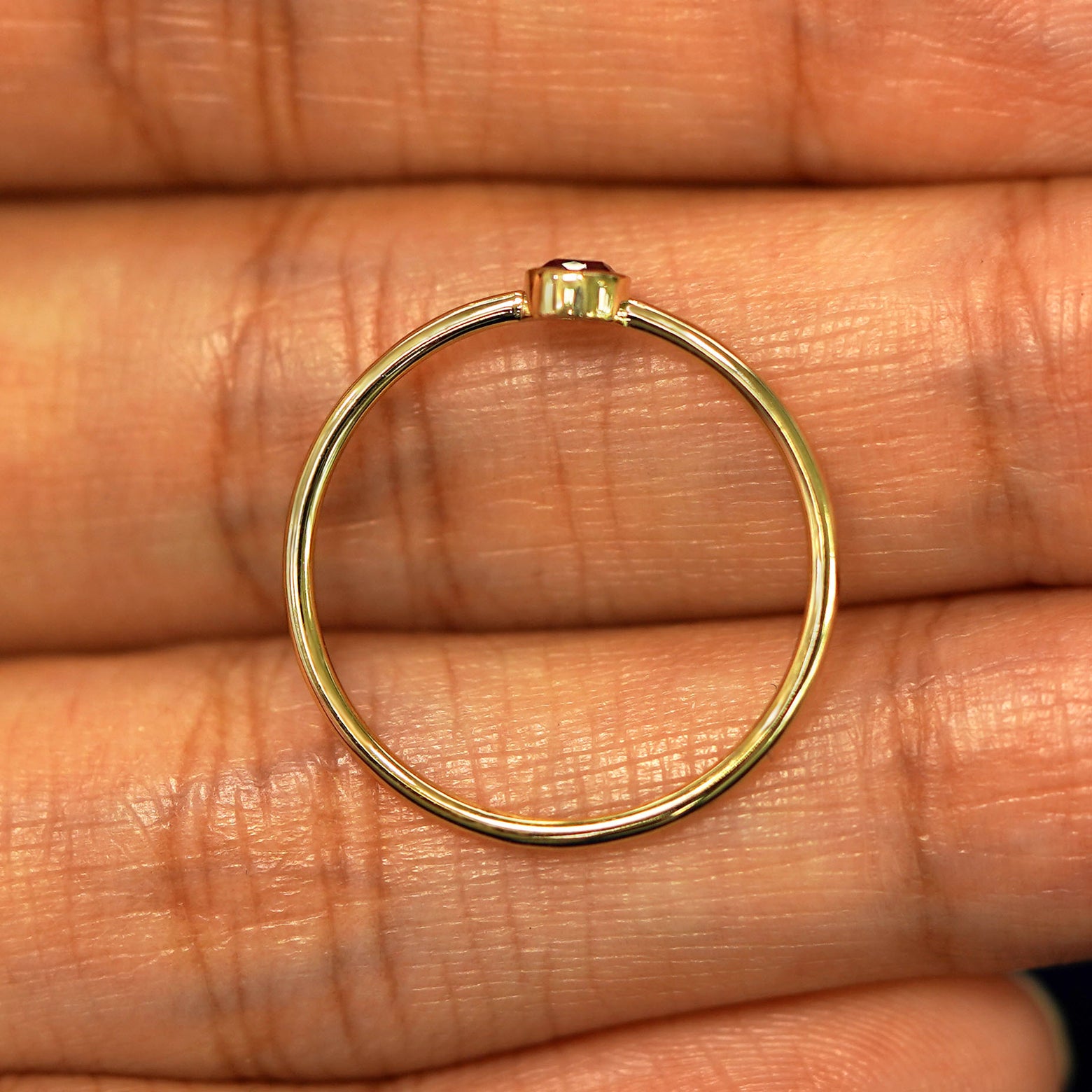 A yellow gold Garnet Ring in a model's hand showing the thickness of the band
