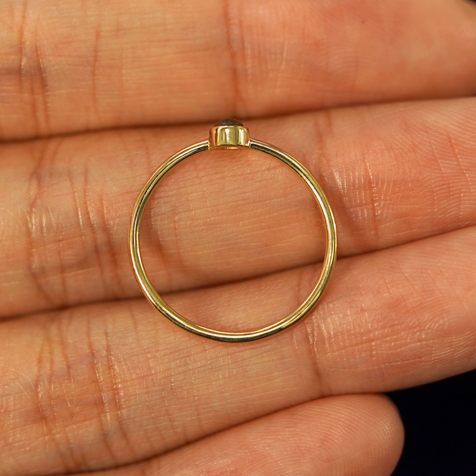 A yellow gold Labradorite Ring in a model's palm showing the thickness of the band