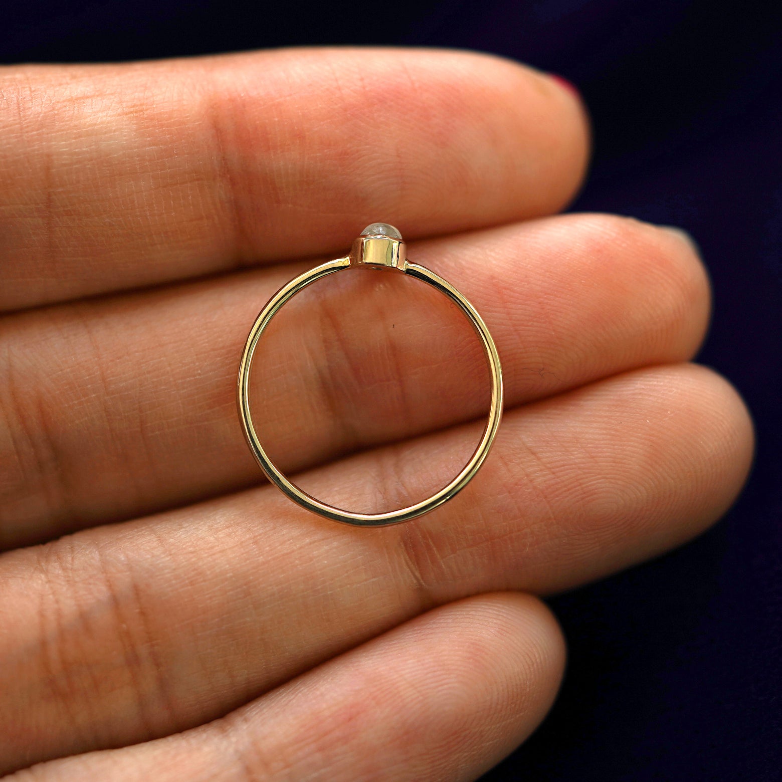 A yellow gold Moonstone Ring in a model's hand showing the thickness of the band