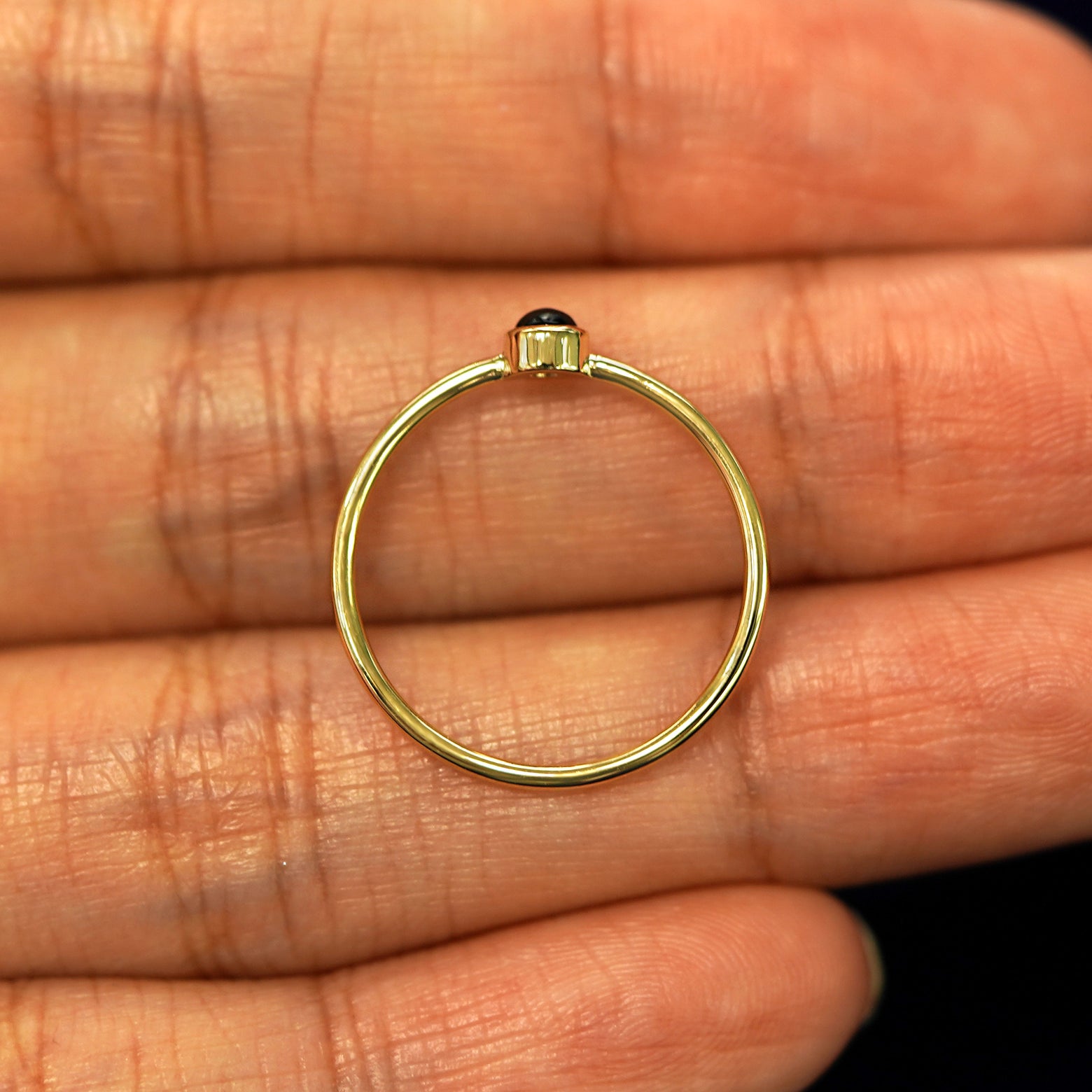 A yellow gold Onyx Ring in a model's hand showing the thickness of the band