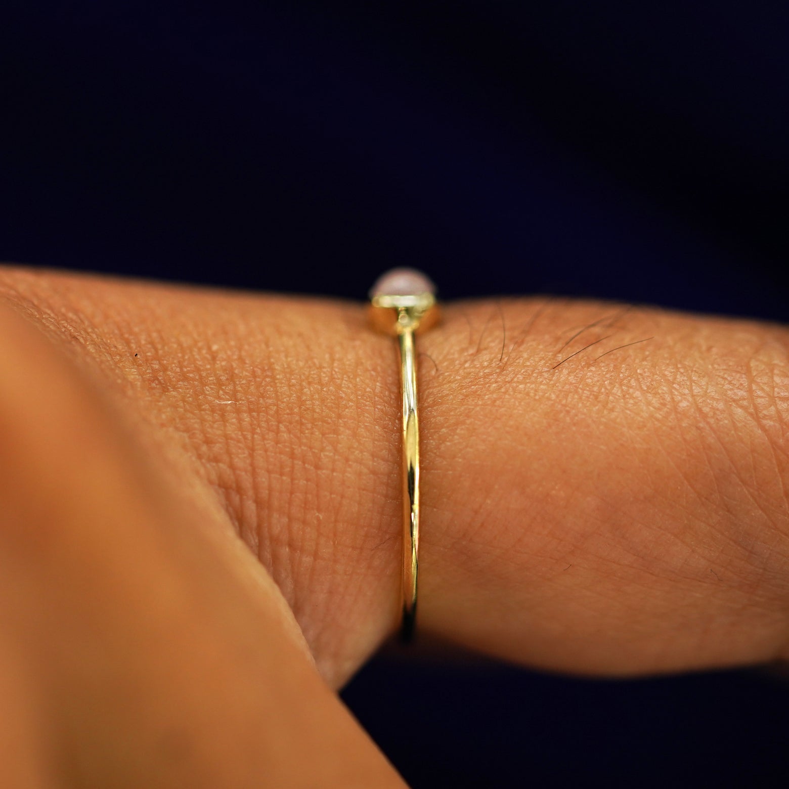 Side view of a model's finger wearing a yellow gold Rose Quartz Ring