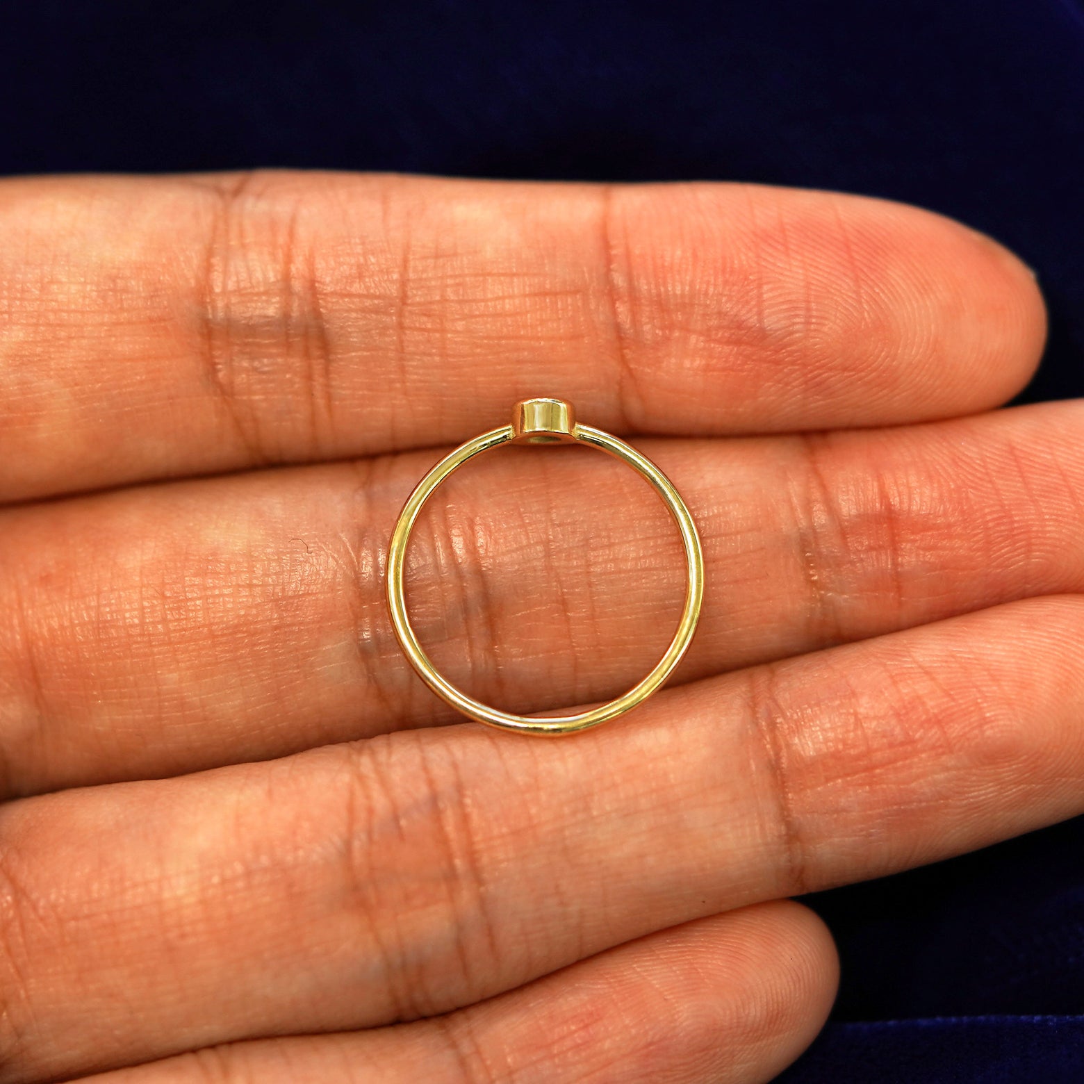 A 14k yellow gold Ruby Ring laying in on a models fingers to show the thickness of the band