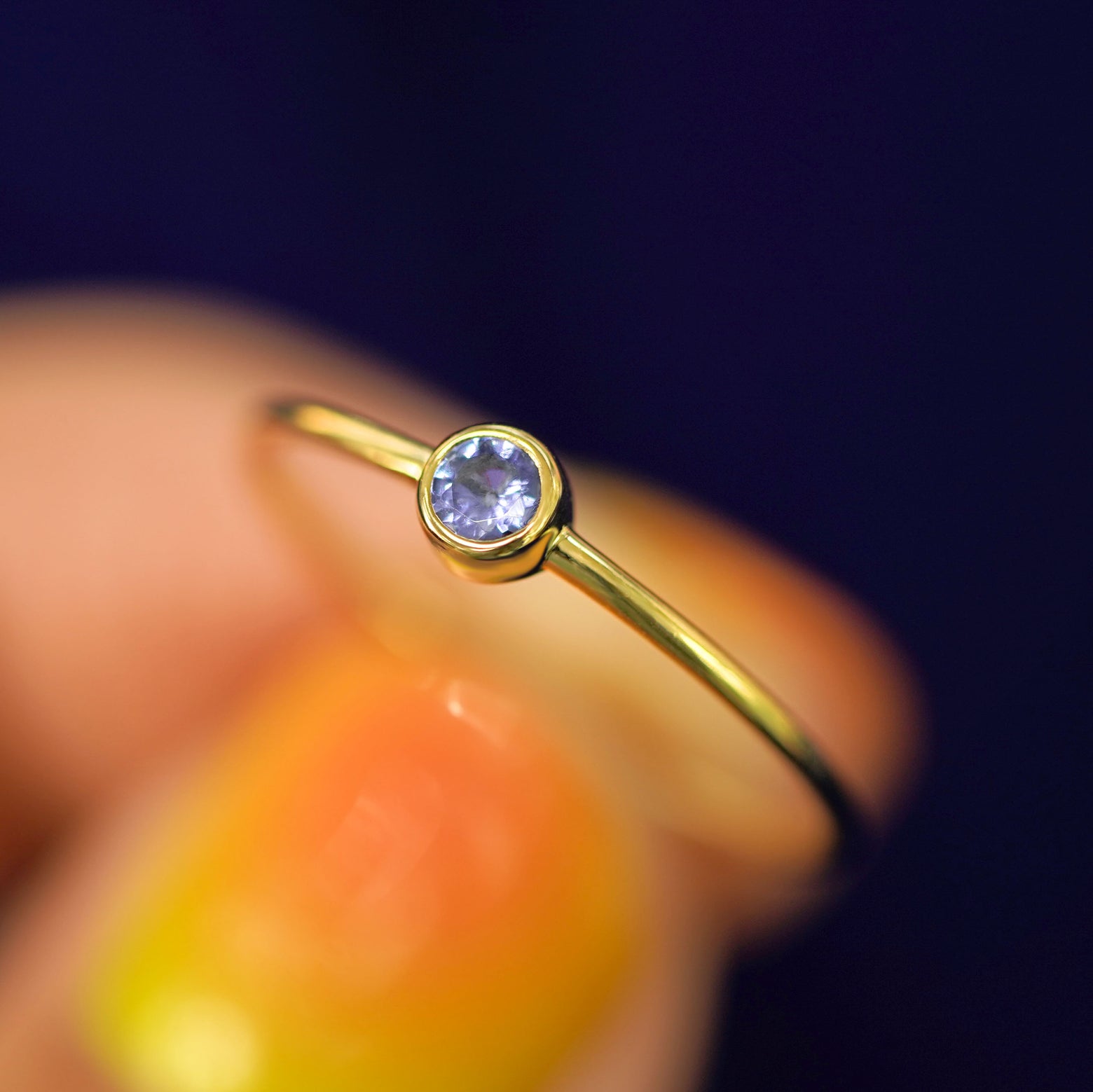 A model holding a Tanzanite Ring tilted to show the details of the bezel setting