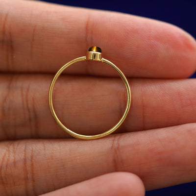 A yellow gold Tiger Eye Ring in a model's hand showing the thickness of the band