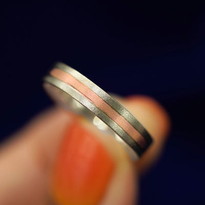 A model holding an Inlay Band titled to show the detail of the inlaid gold