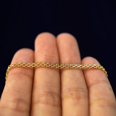 A yellow gold Bismarck Chain resting on a model's fingers