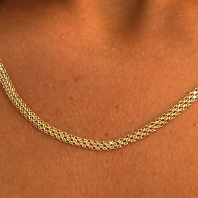 Close up view of a model's neck wearing a solid 14k yellow gold Bismarck Chain