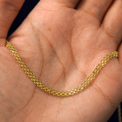 A yellow gold Bismarck Chain draped on a model's palm