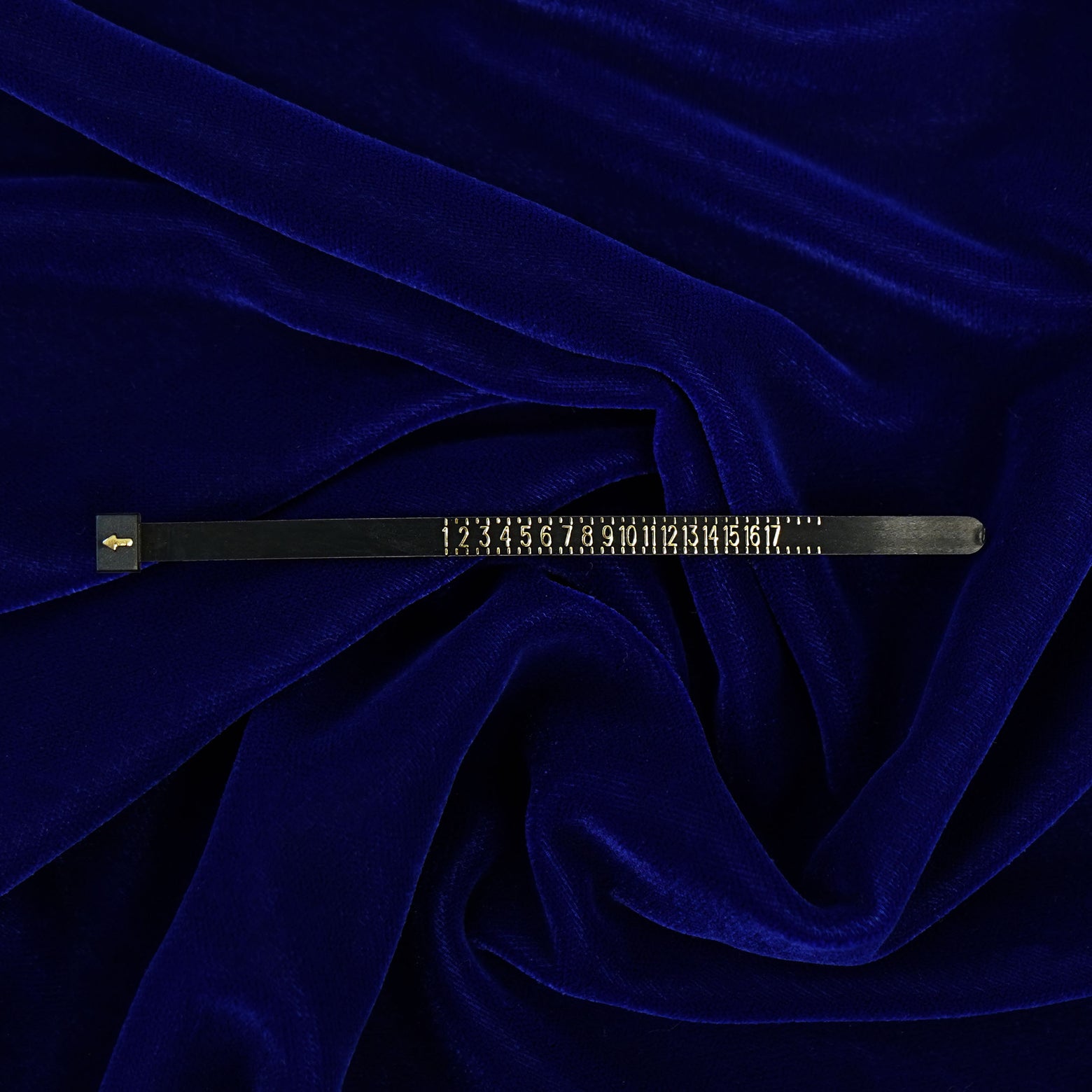 An Automic Gold Ring Sizer laying straight on a dark blue background