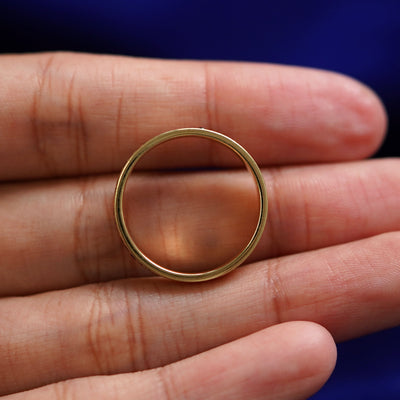 A yellow gold Endless Diamond Band in a model's hand showing the thickness of the band