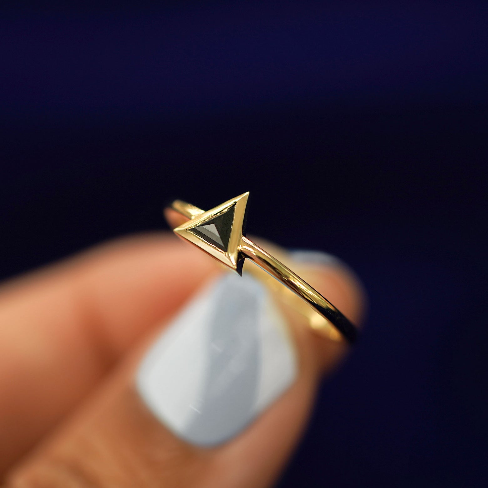 A model holding a Trillion Black Diamond Ring tilted to show the details of the thick bezel setting