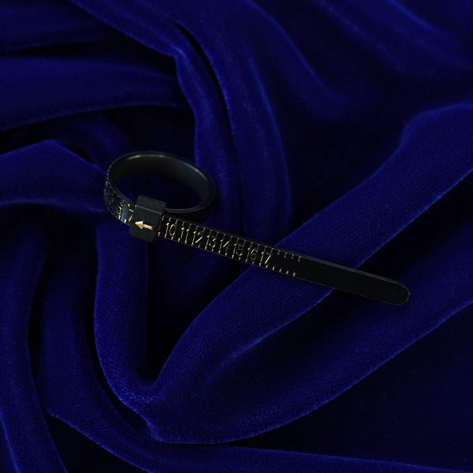 A black Ring Sizer with gold lettering indicating ring size 7 sitting on a dark blue background