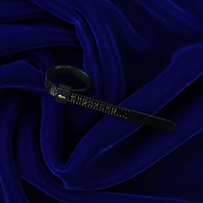 A black Ring Sizer with gold lettering indicating ring size 7 sitting on a dark blue background