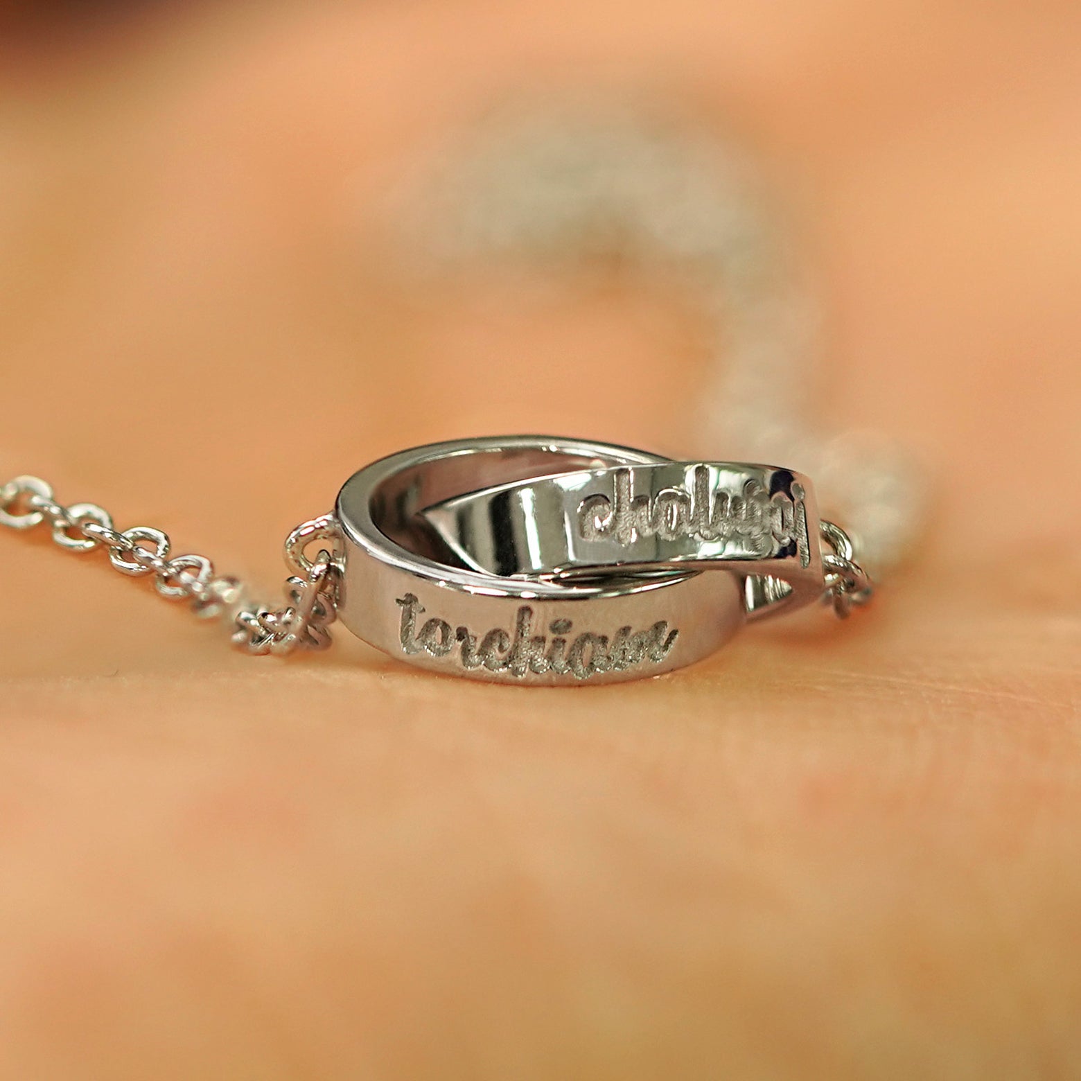 A solid white gold Bound Together Necklace showing engraved names on the outside of both rings