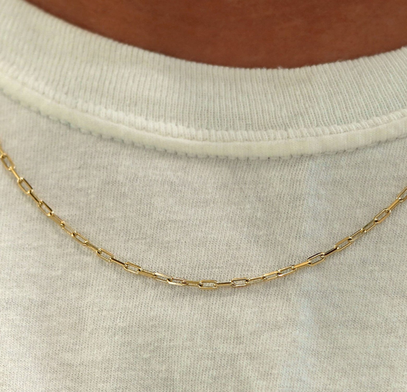 Close up view of a model in a white shirt wearing a solid yellow gold Butch Chain