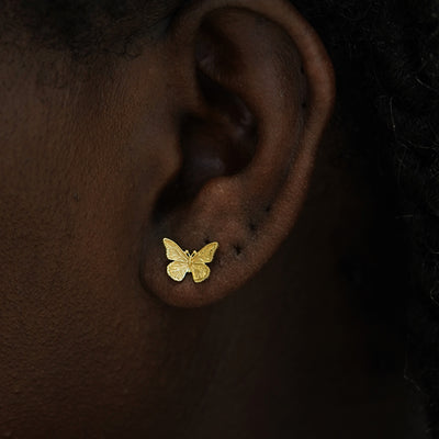 Close up view of a model's ear wearing a 14kv gold Butterfly Earring