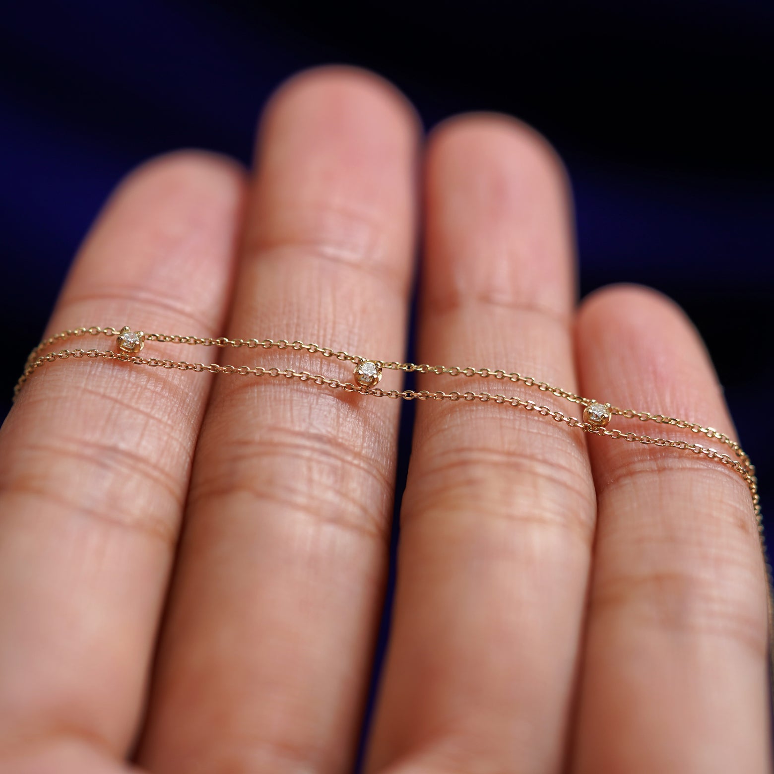 A yellow gold 3 Diamond Cable Bracelet resting on a model's fingers