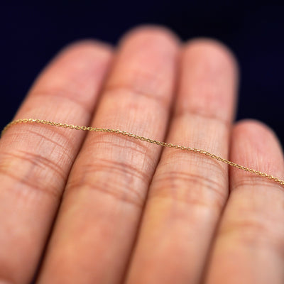 A yellow gold Cable Chain resting on a model's fingers