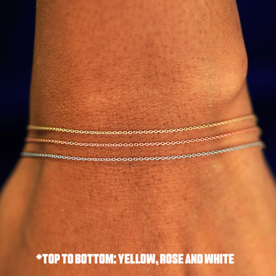 Close up view of a model's wrist wearing three versions of the Cable Necklace in yellow, rose, and white gold