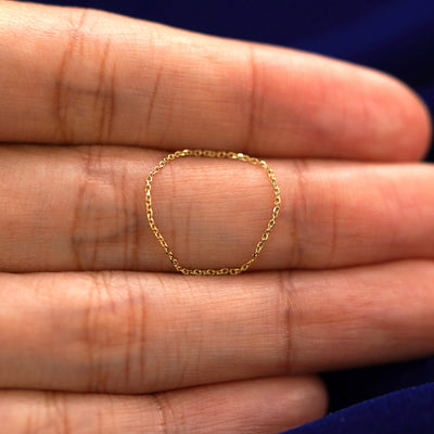 A yellow gold Cable Ring in a model's hand showing the thickness of the chain