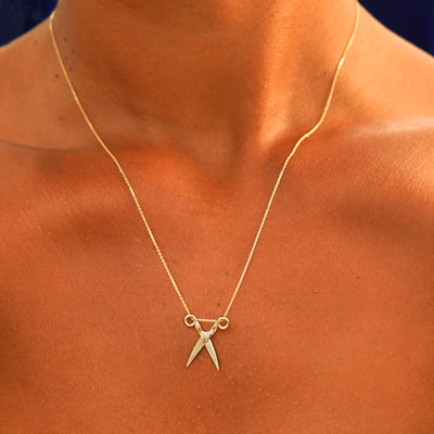 A model's neck wearing a solid 14k yellow gold Scissors Necklace