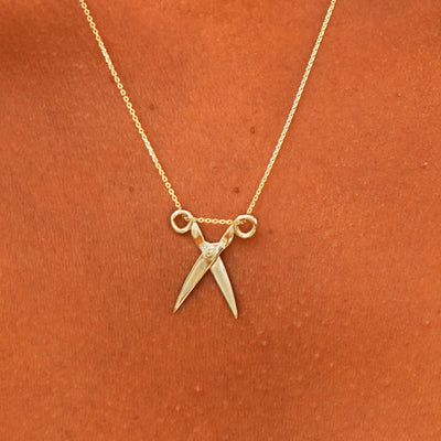 Close up view of a model's neck wearing a solid 14k yellow gold Scissors Necklace