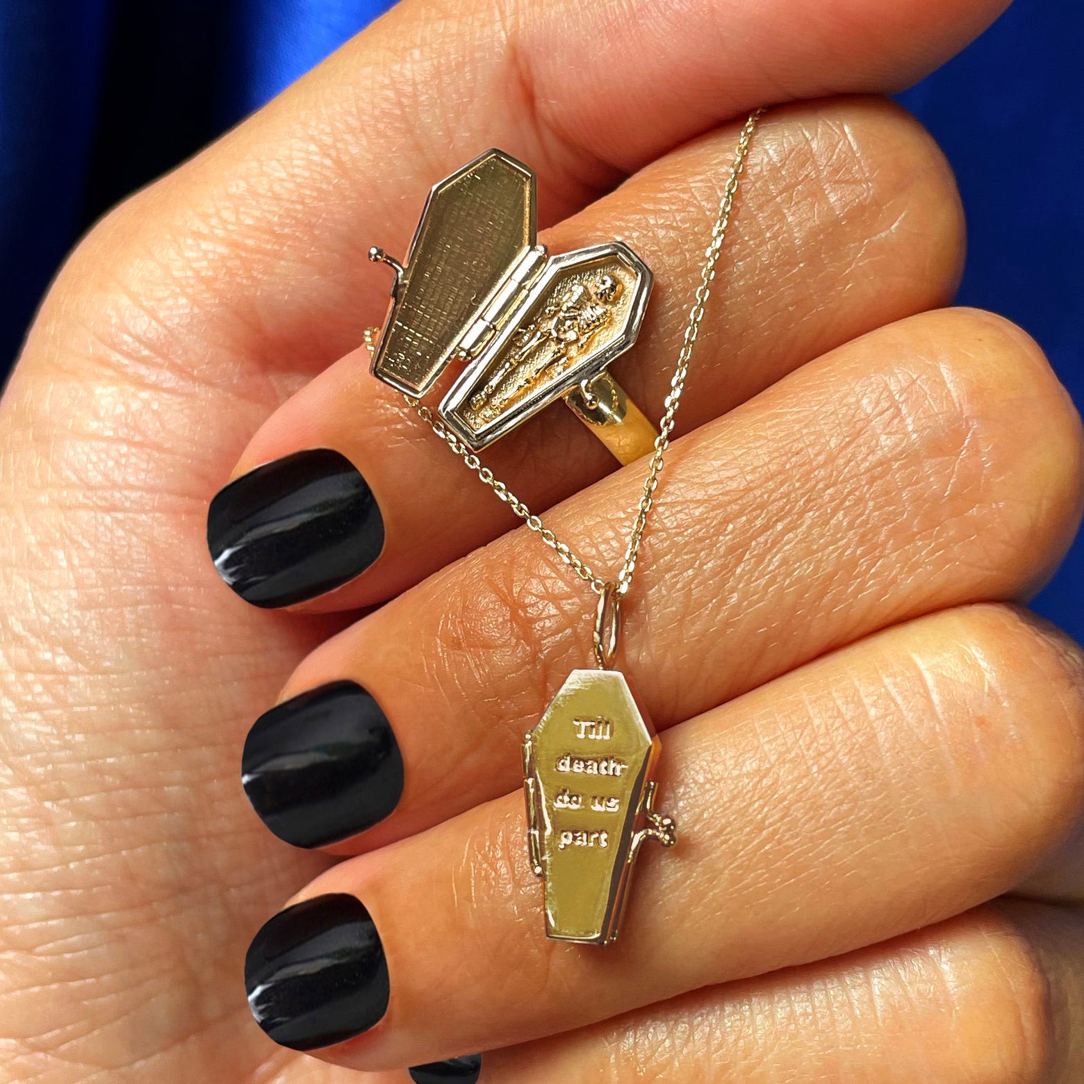 A model with painted black nails holding a Cable Chain with a Coffin Charm while wearing a Coffin Ring