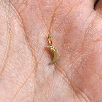 A 14k gold Moon Charm for chain resting in a model's palm to show the underside of the charm