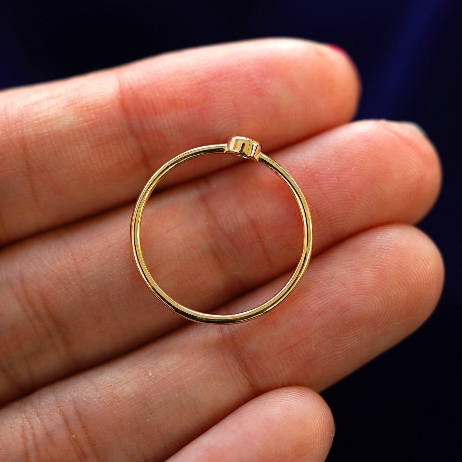 A yellow gold Champagne Diamond Ring in a model's hand showing the thickness of the band