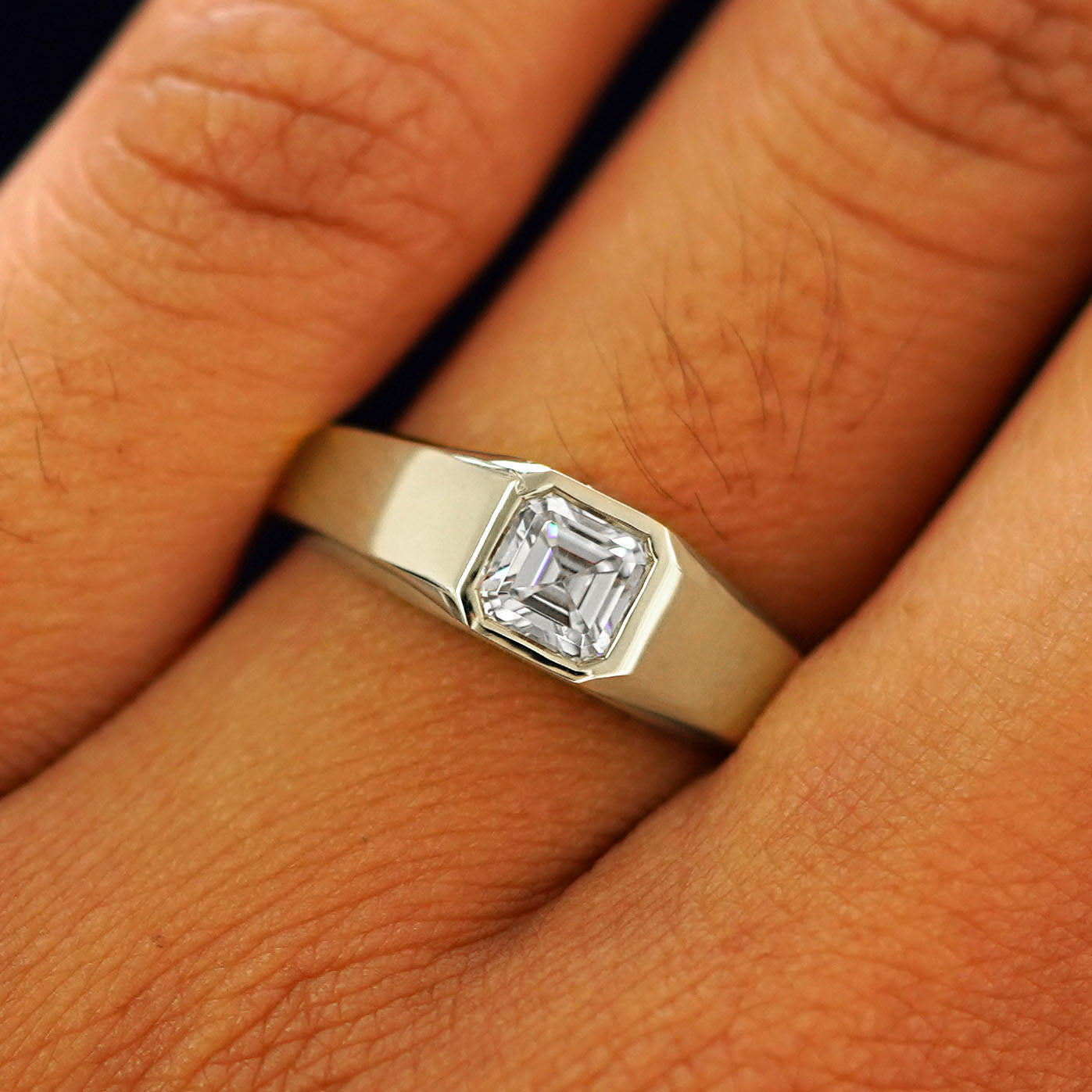 Close up view of a model's fingers wearing a champagne gold white Asscher Moissanite Signet Ring