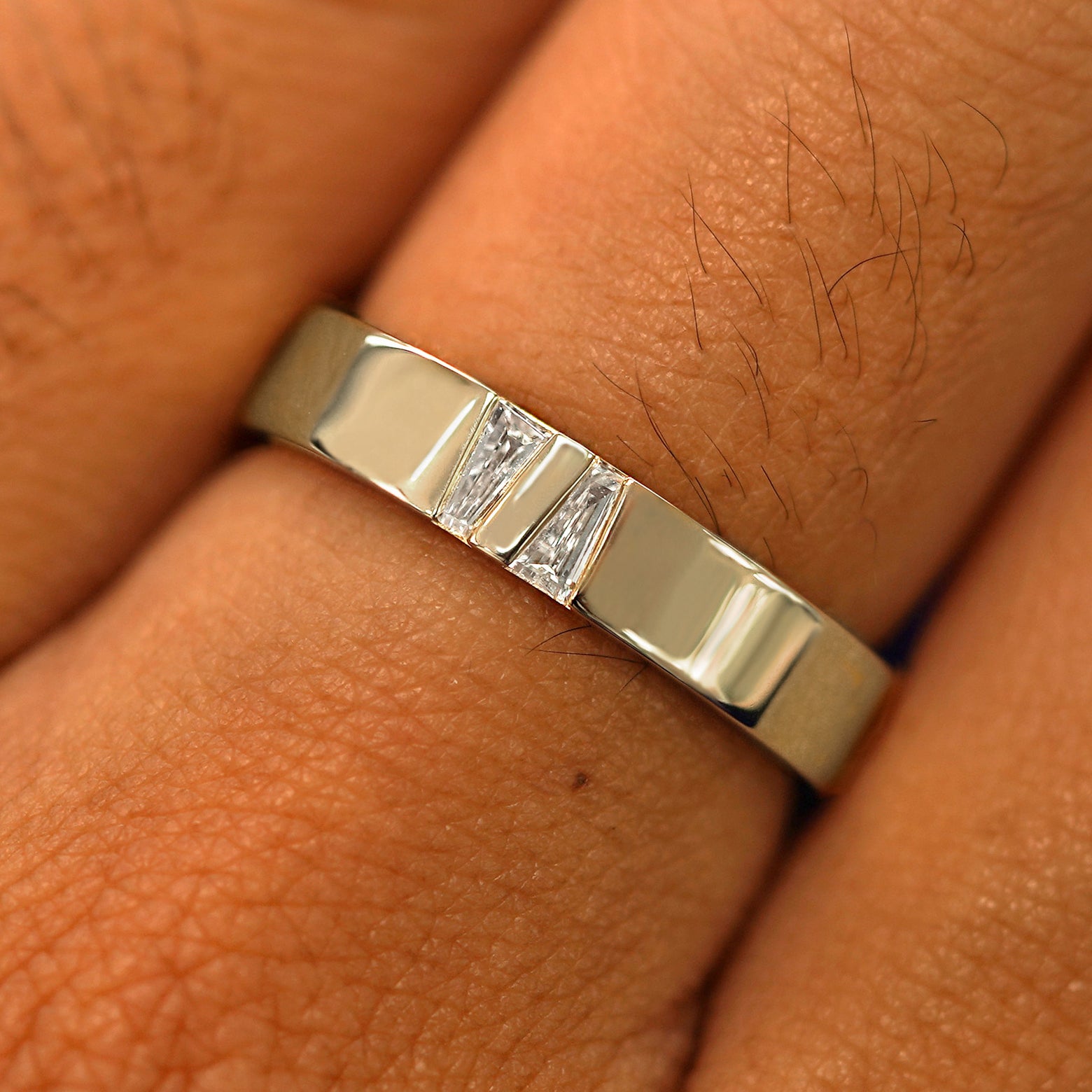 Close up view of a model's hand wearing a solid champagne gold Double Baguette Diamond Band