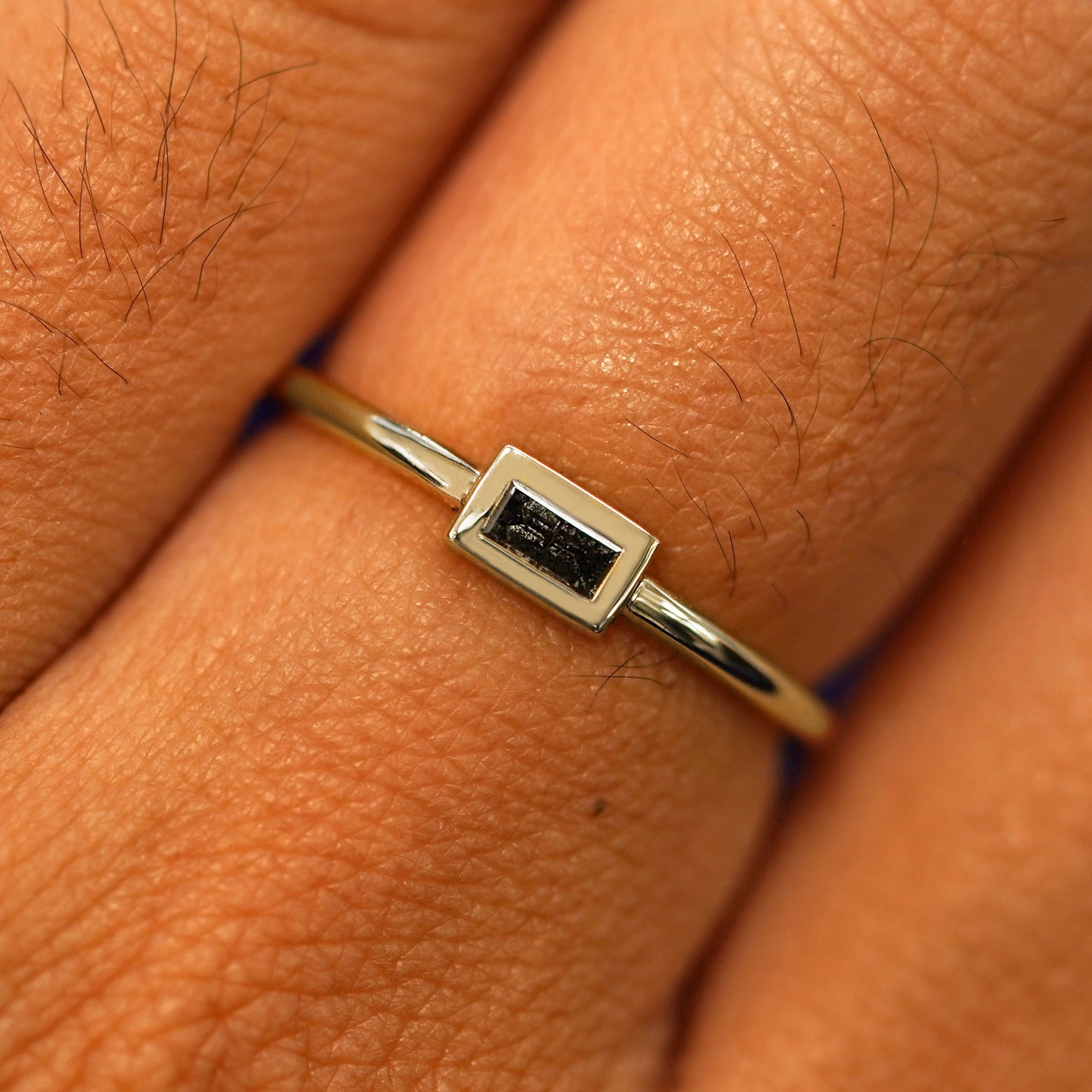 Close up view of a model's fingers wearing a 14k champagne gold Baguette Salt and Pepper Diamond Ring