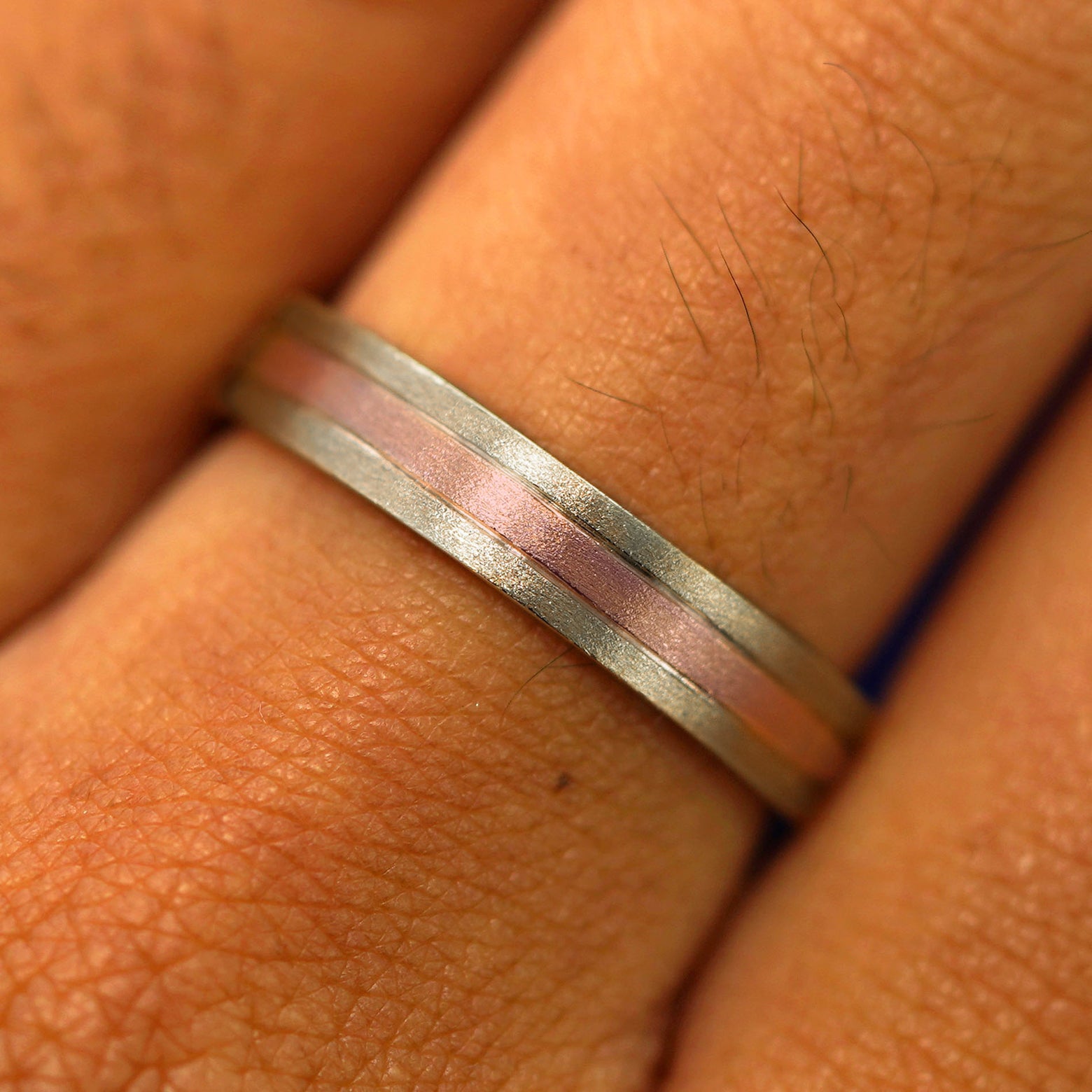 Close up view of a model's fingers wearing a 14k solid champagne gold with rose gold Inlay Band