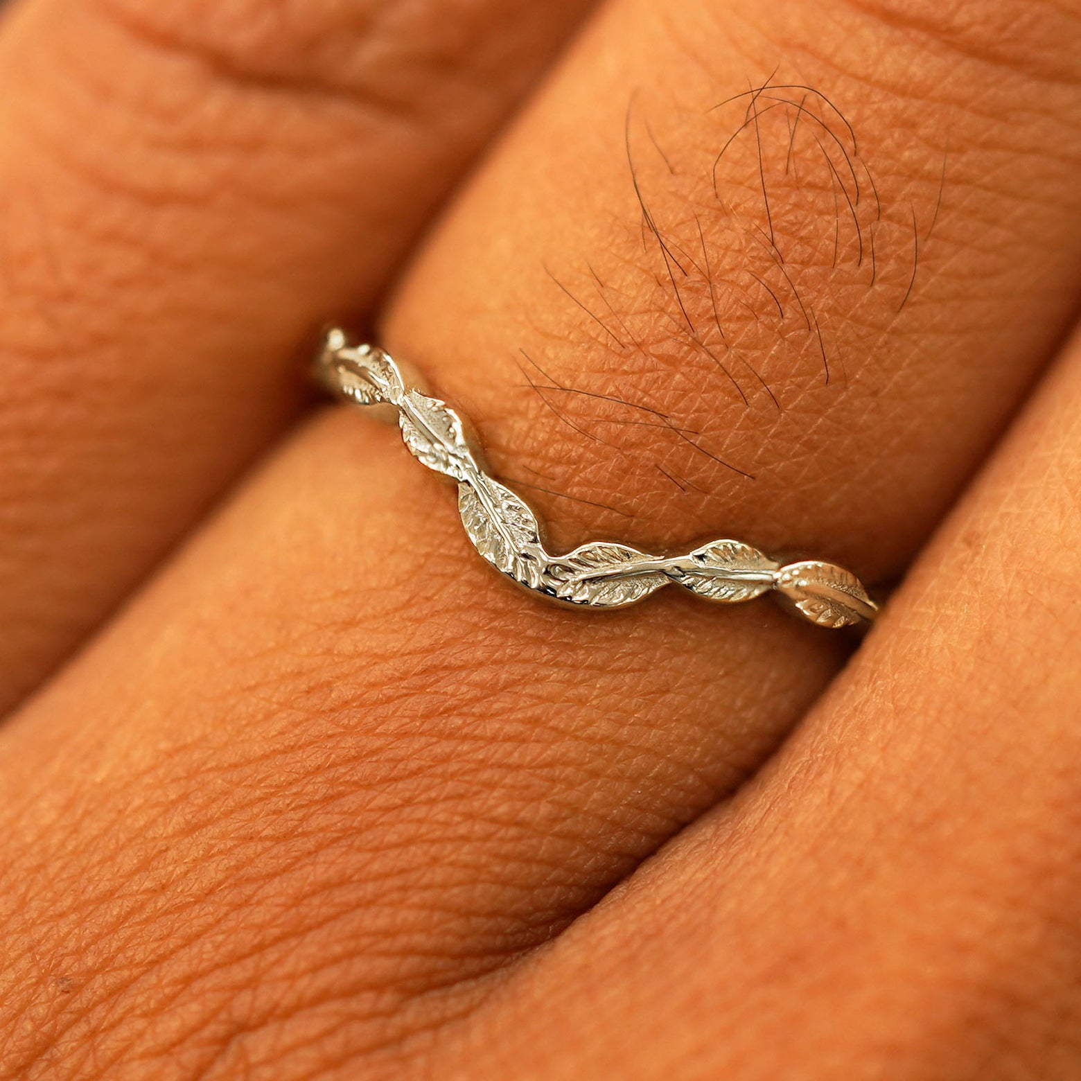 Close up view of a model's fingers wearing a 14k champagne gold Chevron Leaves Band