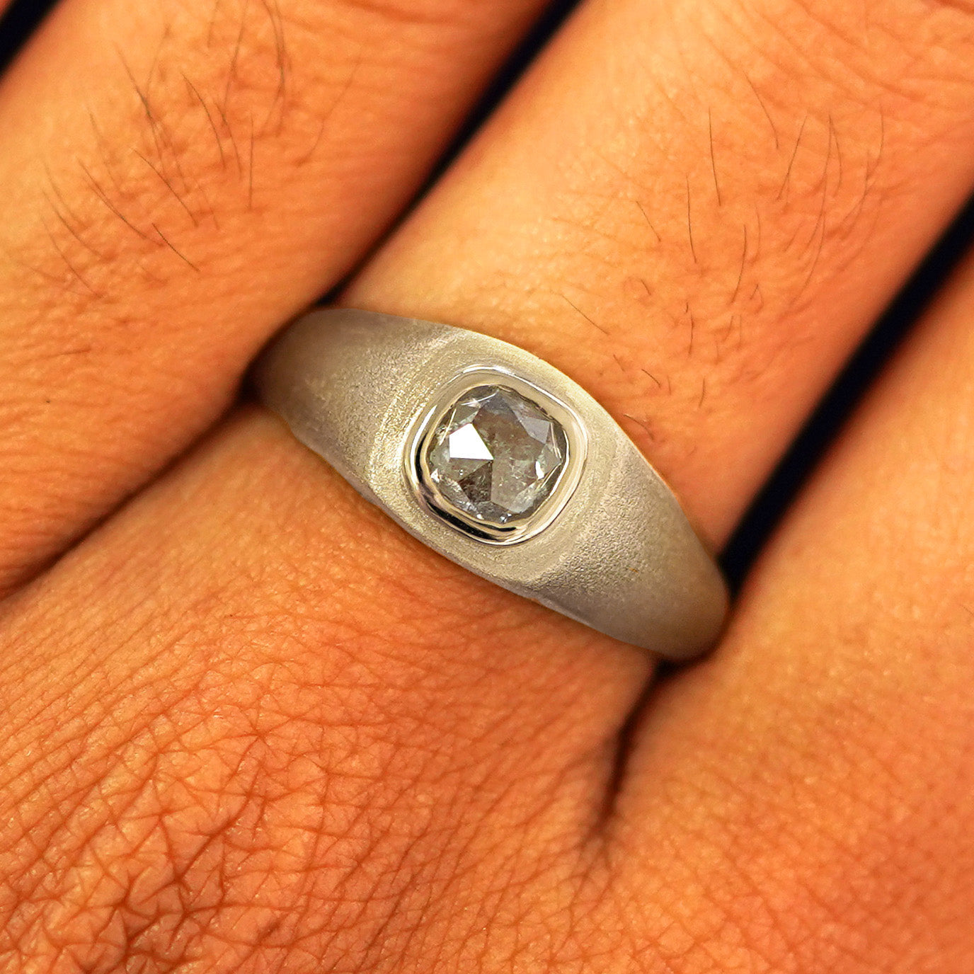 Close up view of a model's fingers wearing a 14k champagne gold Cushion Salt and Pepper Diamond Signet Ring