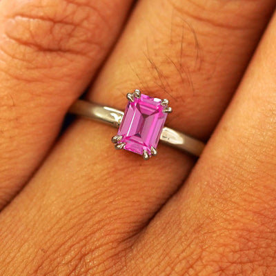 Close up view of a model's fingers wearing a 14k champagne gold Emerald Cut Pink Sapphire Ring