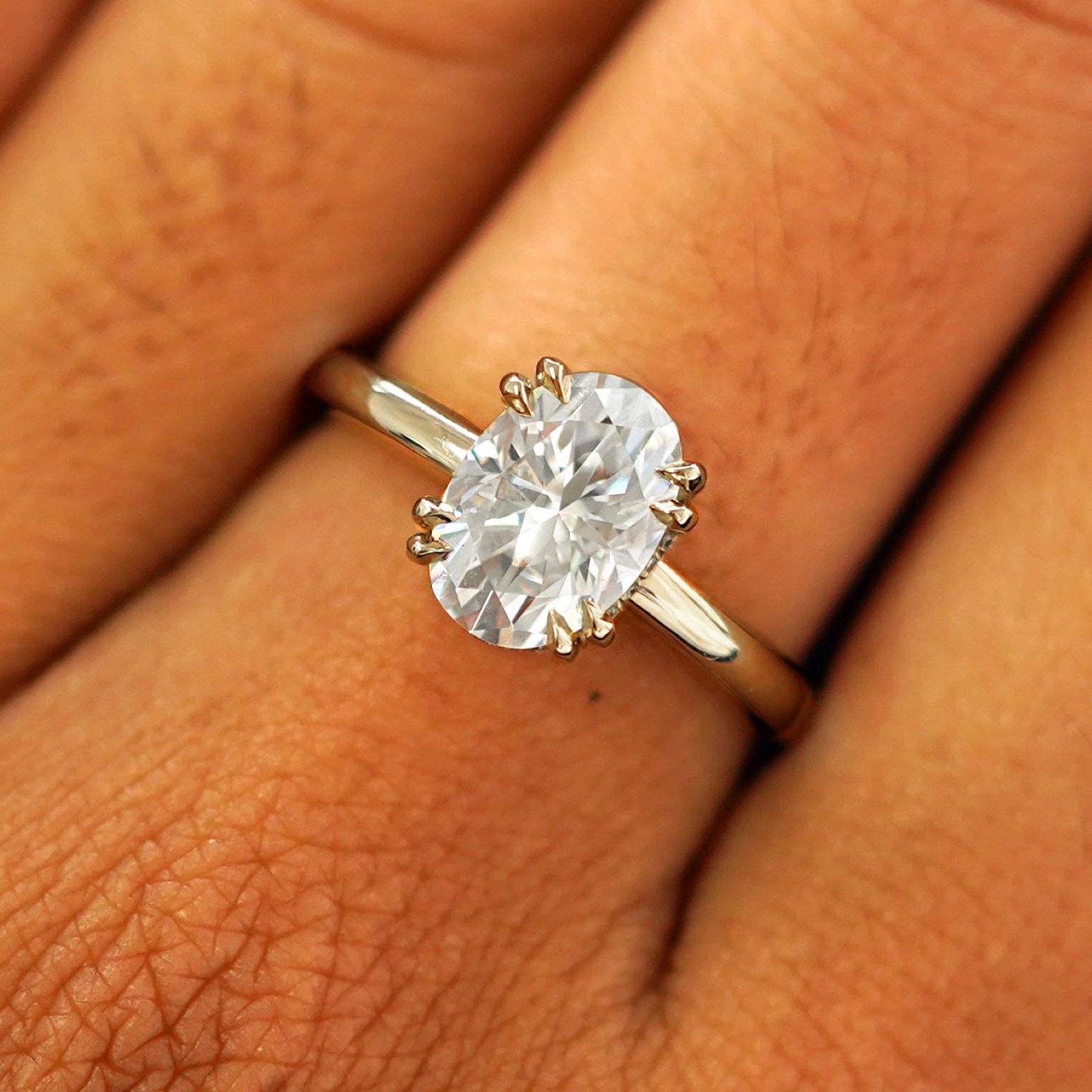 Close up view of a model's fingers wearing a 14k champagne gold Oval Moissanite Halo Ring