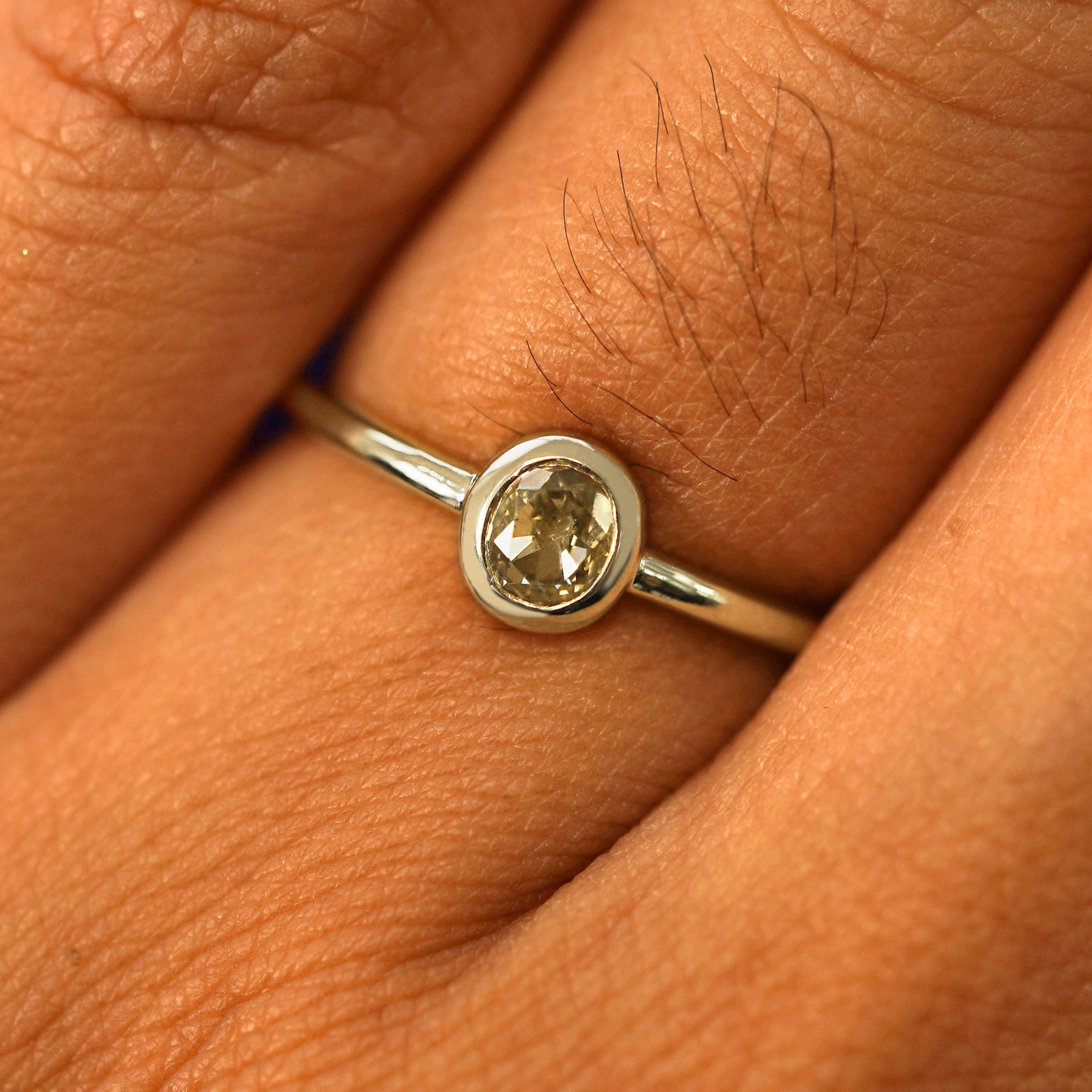 Close up view of a model's fingers wearing a 14k champagne gold Oval Champagne Diamond Ring