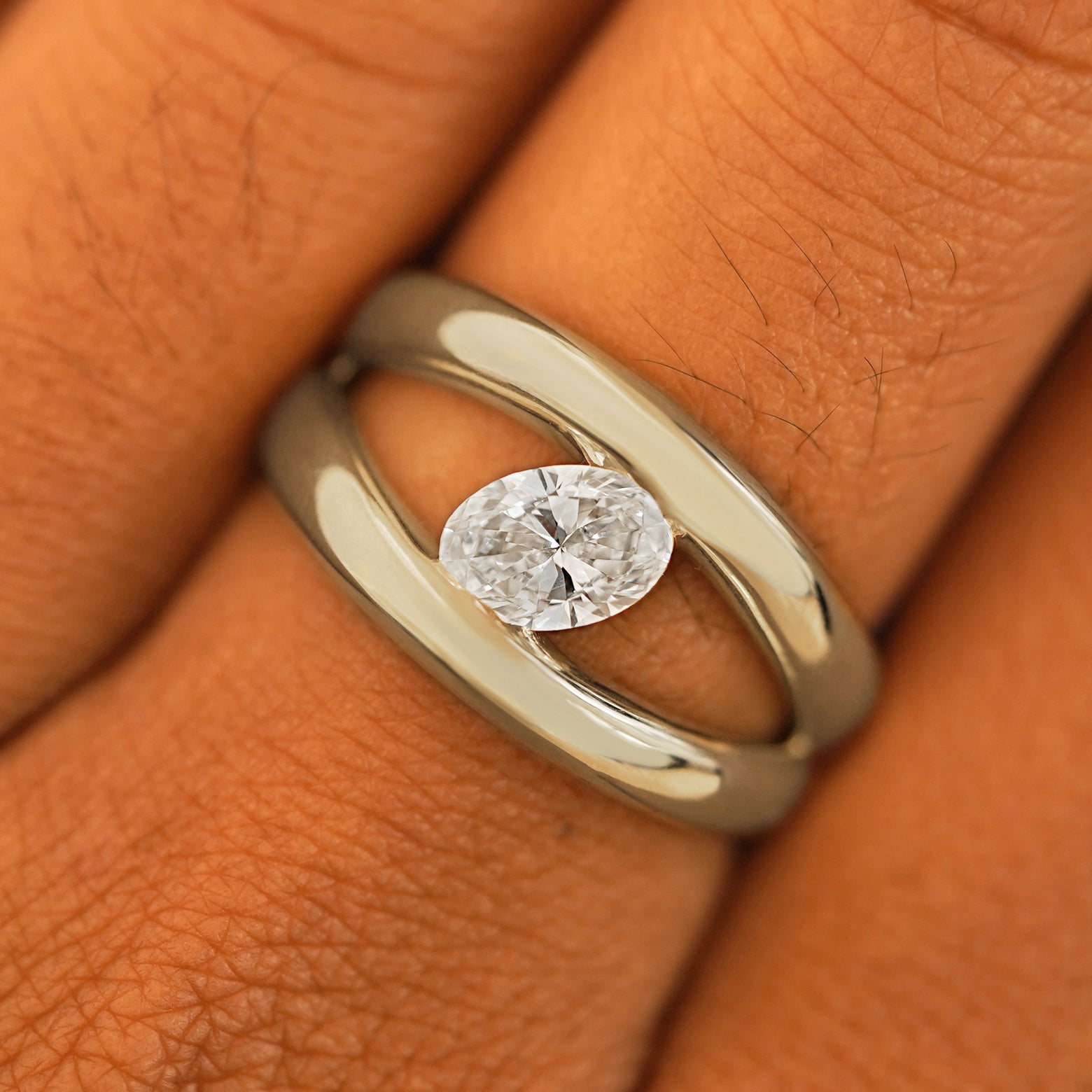 Close up view of a model's fingers wearing a 14k champagne gold Oval Lab Diamond Tension Ring