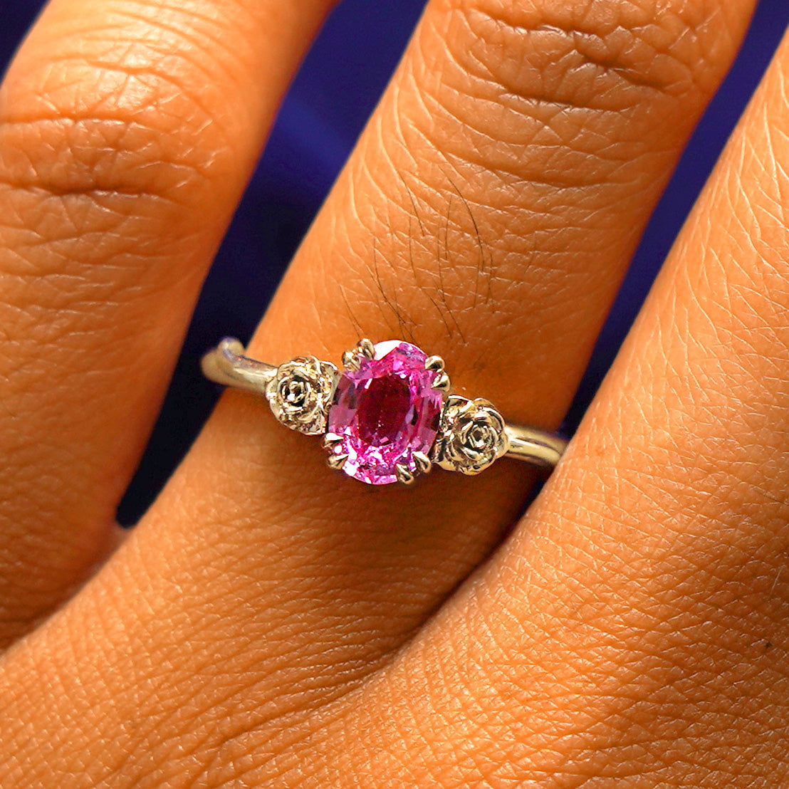 Close up view of a model's fingers wearing a 14k champagne gold Pink Sapphire Roses Ring