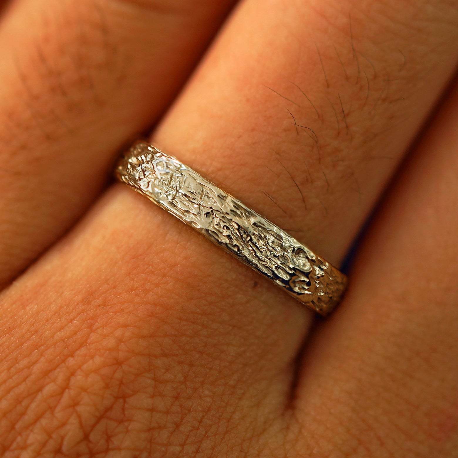 Close up view of a model's fingers wearing a 14k champagne gold Raw Band