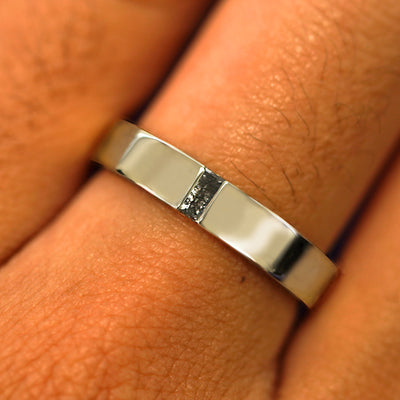 Close up view of a model's hand wearing a solid champagne gold Salt and Pepper Baguette Diamond Band