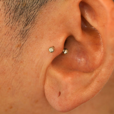 A model's ear wearing a champagne gold Small Curved Barbell in a tragus piercing