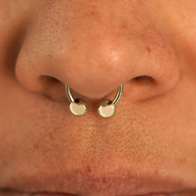 Close up view of a model's nose wearing a 14k champagne gold Small Horseshoe in a septum piercing