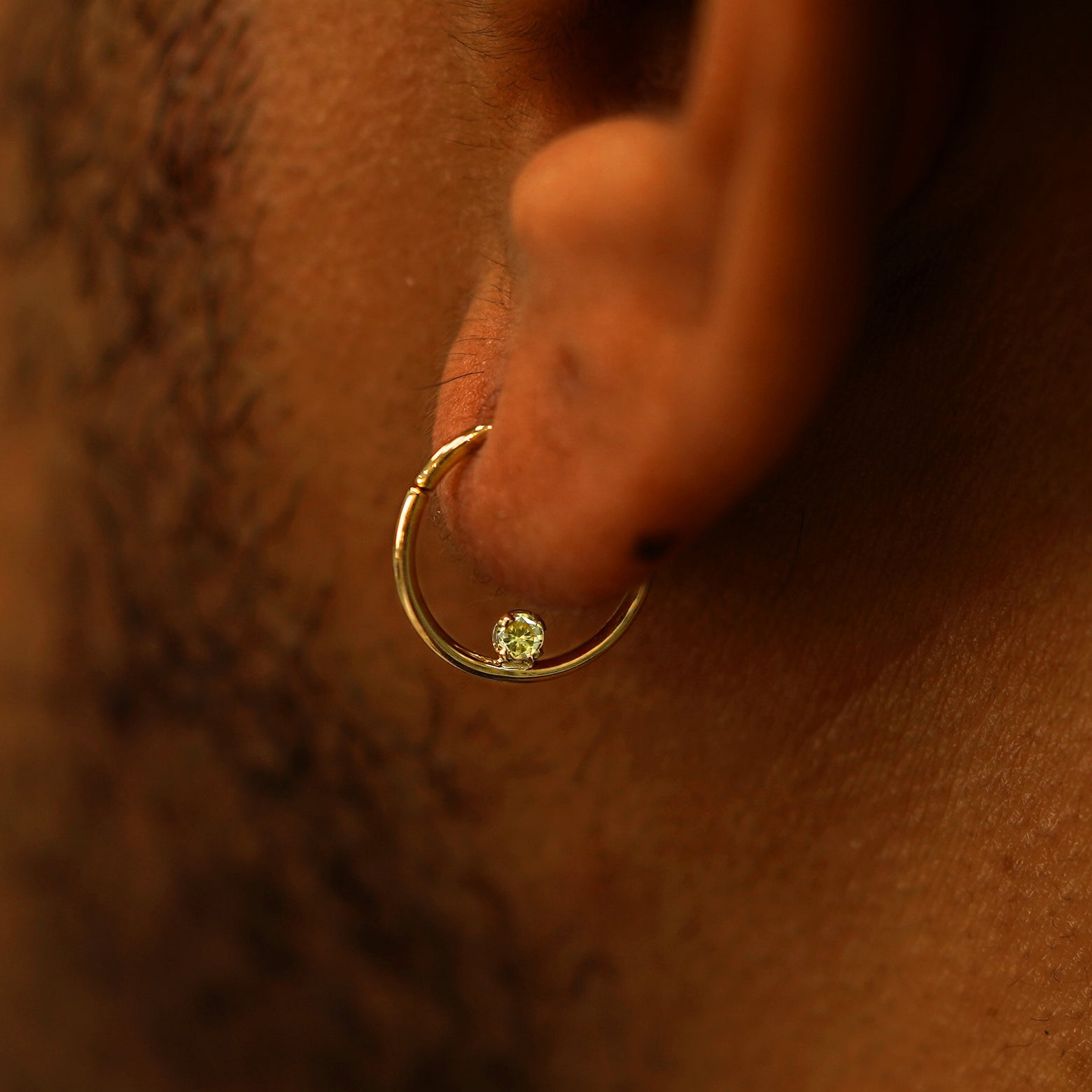 Close up view of a model's ear wearing a citrine Raised Gemstone Septum as a hoop earring