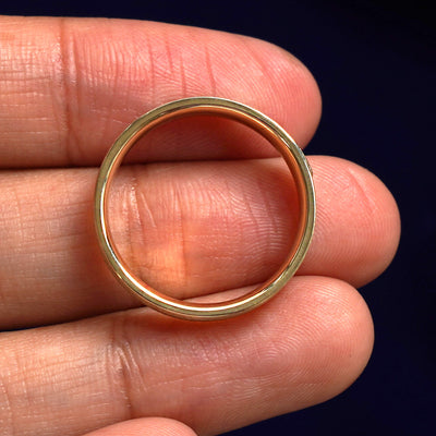 A yellow gold Cloud Diamond Band in a model's hand showing the thickness of the band