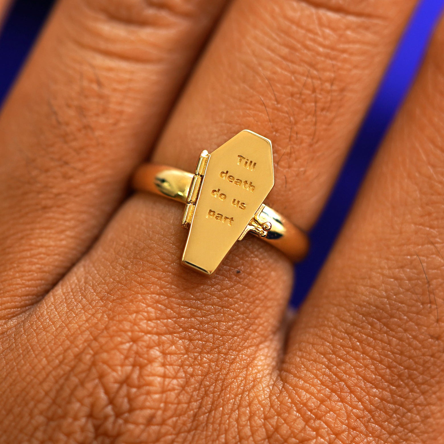 Close up view of a model's hand wearing a yellow gold Coffin Ring in the closed position